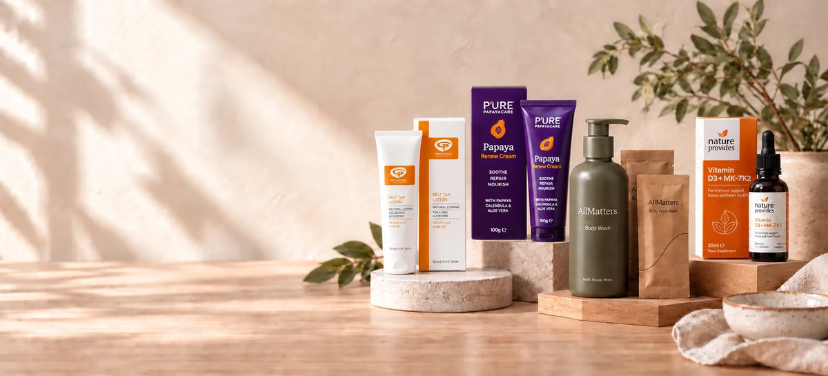 A curated collection of natural health, skincare and wellness products from Entirely Pure such asPure Encapsulations and Dr. Brande's Natural Health, displayed on wooden risers on a warm beige background with soft leaf shadows.